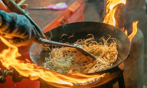 Stir-frying noodles over an open flame
