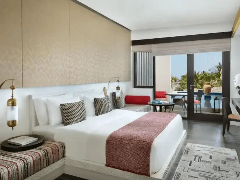 A chic and modern resort room with vibrant accents and a balcony at Al Baleed Resort Salalah.