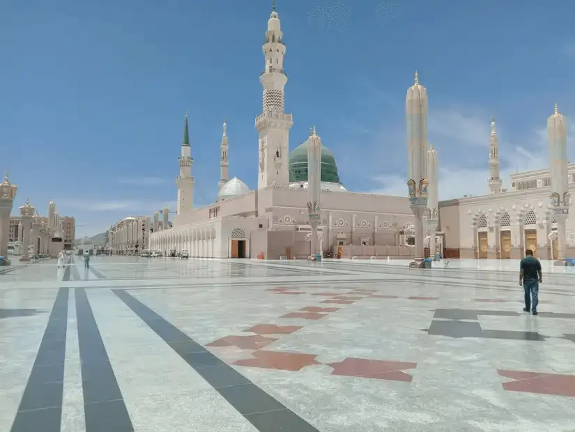 A wide-angle shot of Al-Masjid an-Nabawi, featuring its iconic green dome and minarets.