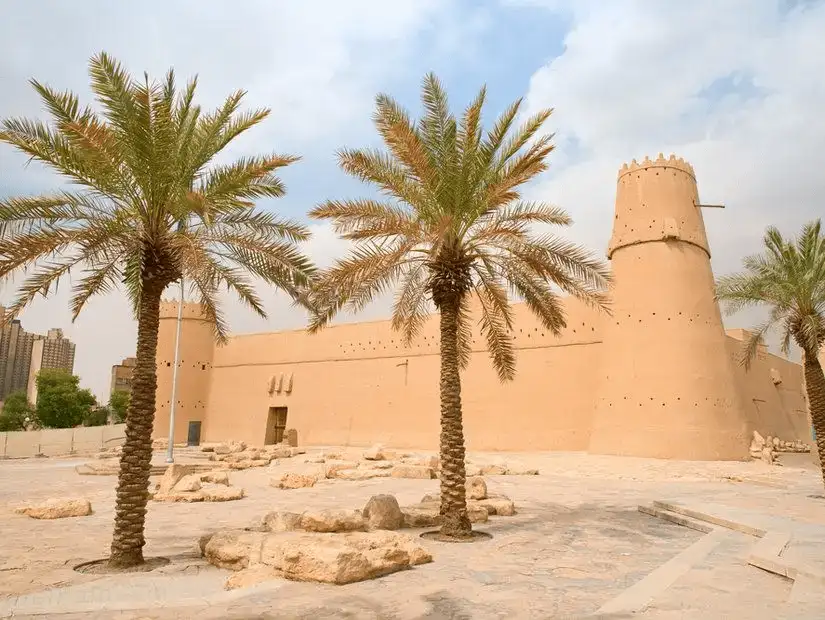 A historic fortress standing with dignity amidst modern palm trees.