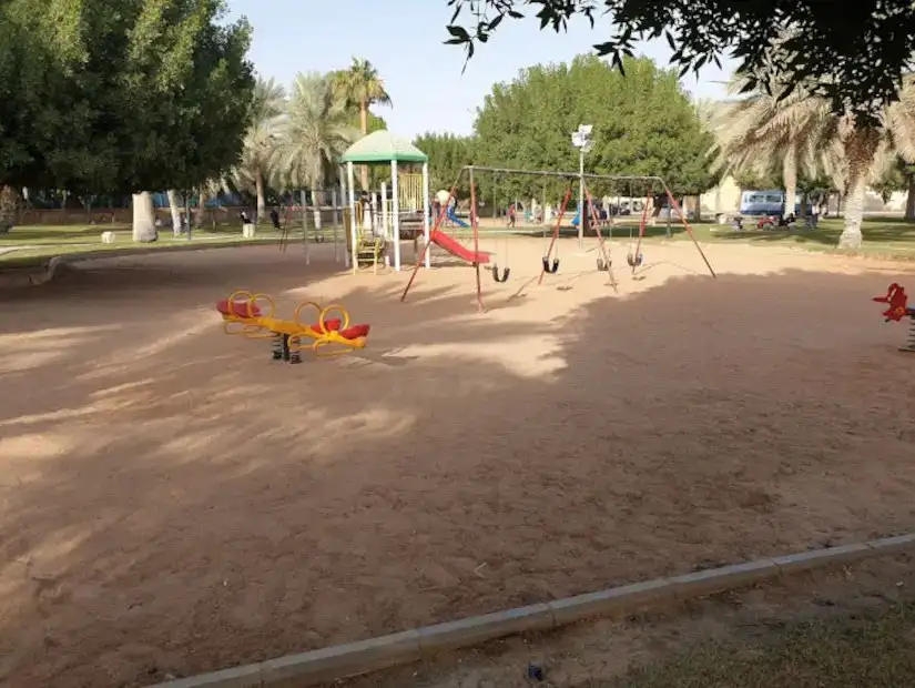 Wide view of a deserted playground with various equipment on a sunny day.