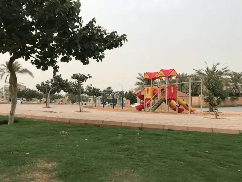 Sunny park view featuring a vibrant children's play area with slides and swings.