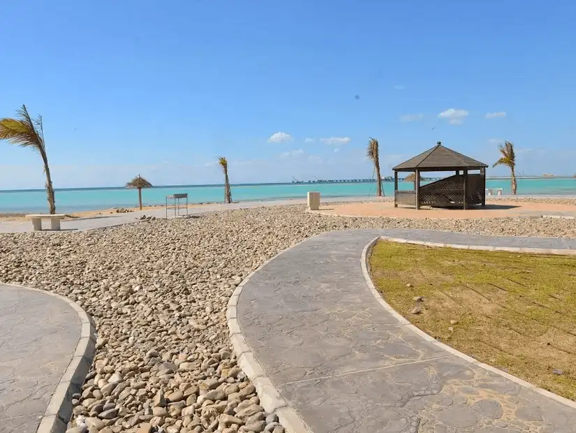 Peaceful beach gazebo on a pebbled shore with a winding path leading to the calm blue waters.