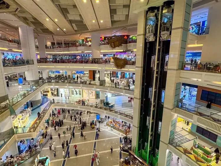 The bustling interior of Aliat Mall, with shops and escalators connecting the different floors.