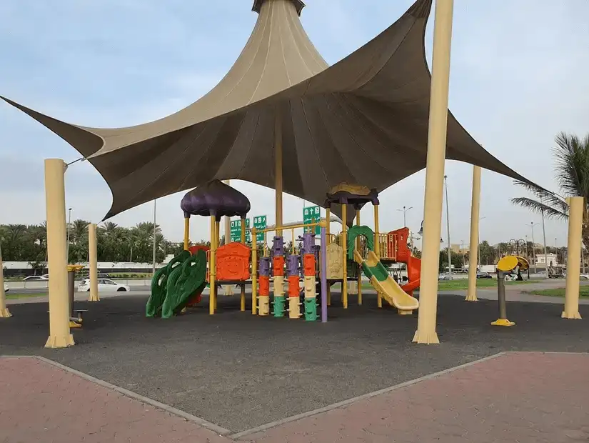 Shaded playground with vibrant equipment under a large canopy in Andalus Park.