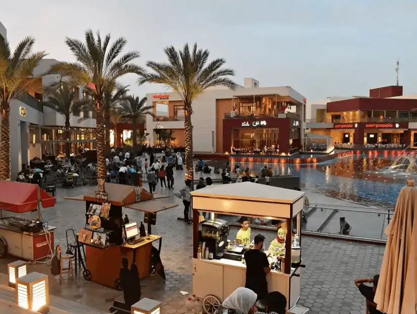 A bustling outdoor plaza at twilight, with families and street food vendors adding to the vibrant community vibe.