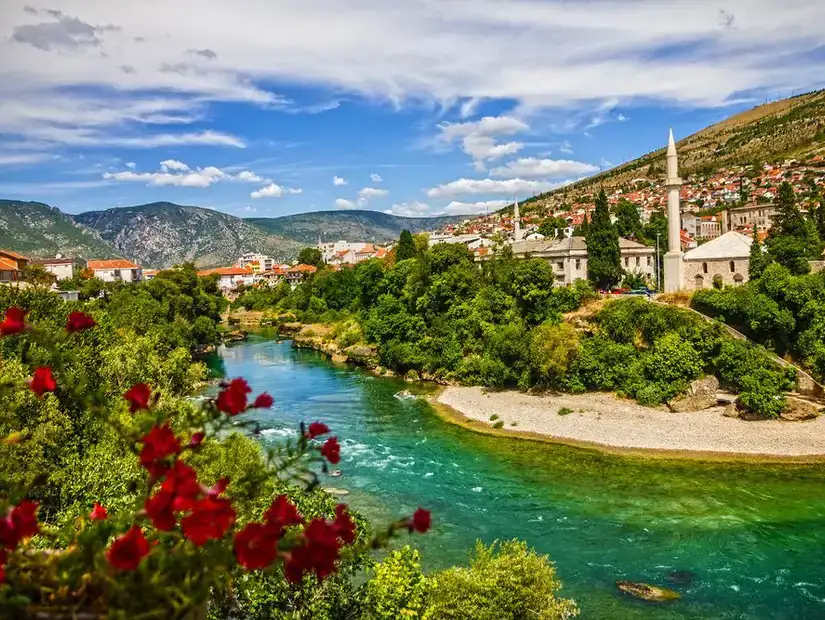 Colorful flowers accentuate the tranquil river in a Bosnian village.