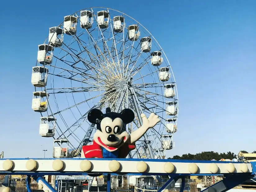 A vibrant amusement park with a character statue greeting visitors at Boudl Land.