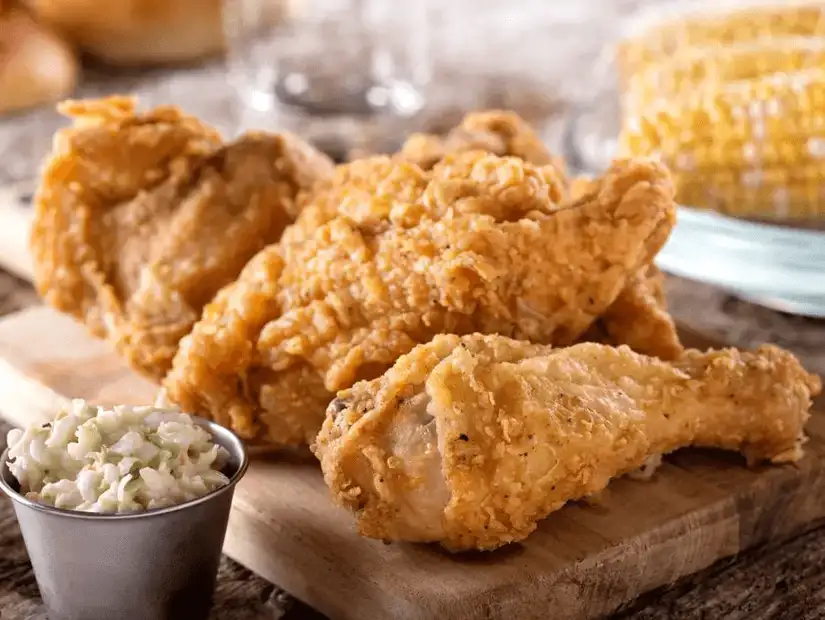 Crispy fried chicken wings served with coleslaw and golden corn – a fast-food favorite.