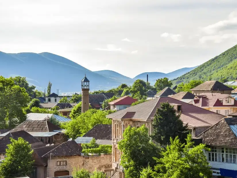 A serene view of Shaki's rooftops with mountains in the background.