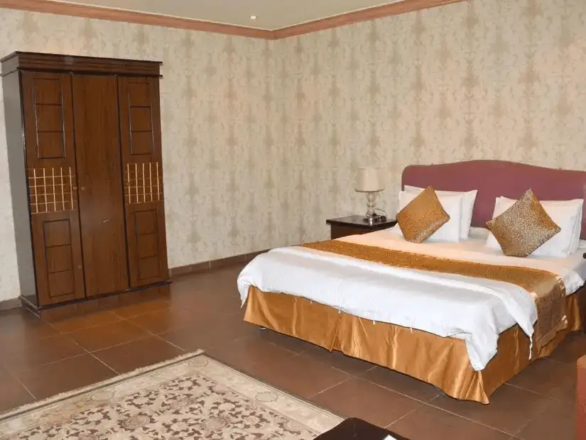 A luxurious hotel room with an elegant canopy bed, plush cushions, and a rich, warm color scheme.