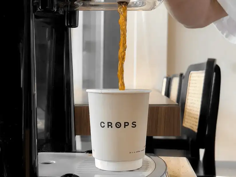 A cup of black coffee being filled from a modern coffee machine, evoking the essence of a fresh brew.