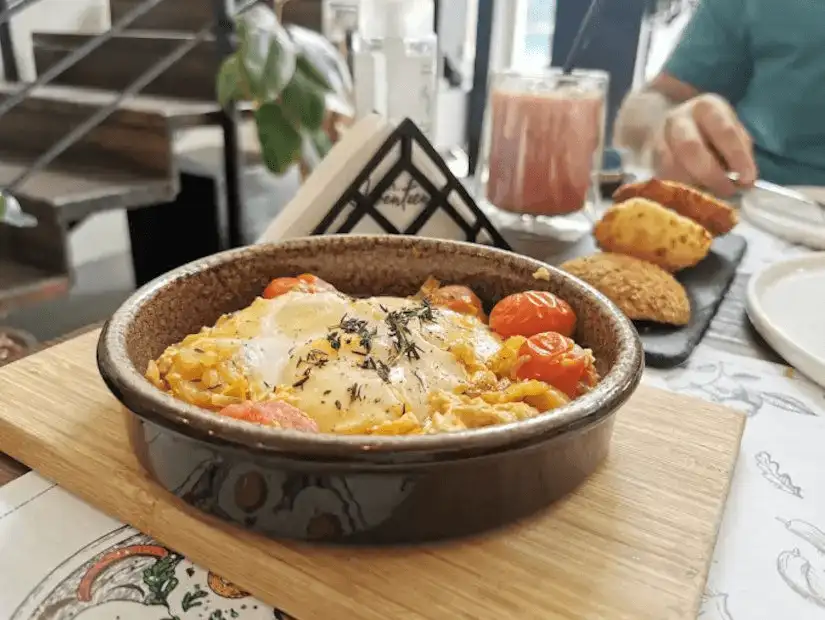 A rustic, baked grain and egg dish garnished with roasted tomatoes.