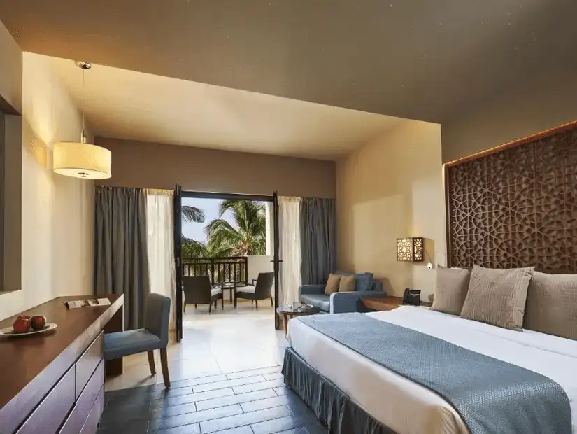 A spacious and inviting hotel room with a view of the palm trees at Fanar Hotel & Residences.