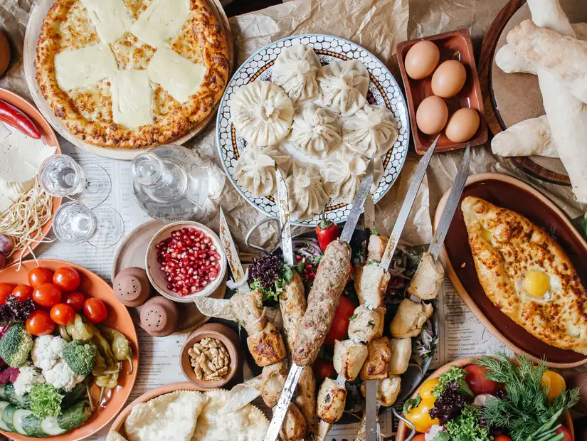 A large table of Georgian food including Kebab, Lula, Lavash, Suluguni cheese, Khachipuri, Khinkali