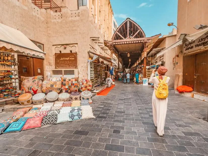 A bustling souk entrance lined with vibrant textile displays and traditional crafts.