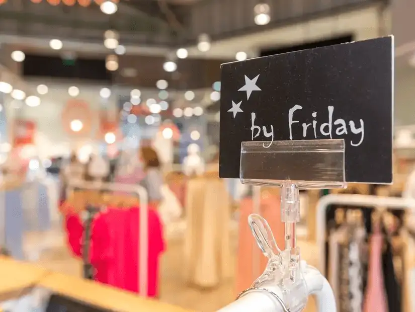 Chalkboard sign announcing 'by Friday' sale in a clothing store.