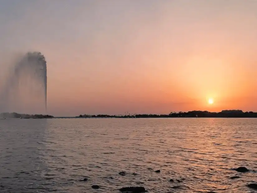 The King Fahad fountain with the sun setting on the horizon.