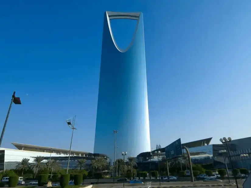 The towering silhouette of Kingdom Tower against a clear blue sky.