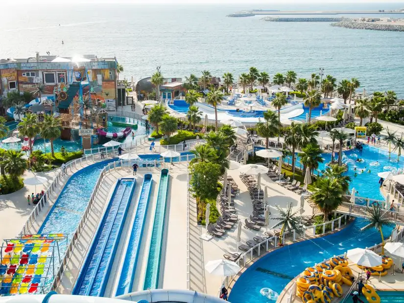 A coastal water park with slides, a pool, and a lazy river overlooking the beach.