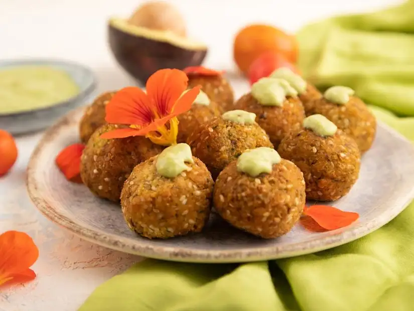 A beautifully presented dish of kofta kebabs, colorful vegetables, and tomato slices, ready to be shared.