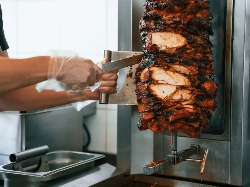 Shawarma being freshly sliced from the rotisserie.