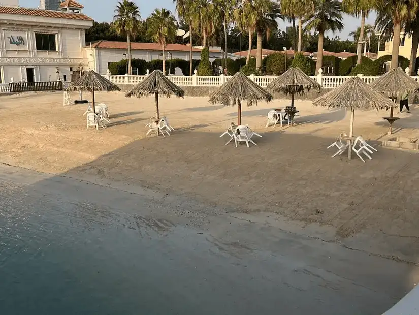 Sandy beach with straw umbrellas offering a quiet retreat by the gentle sea waves.