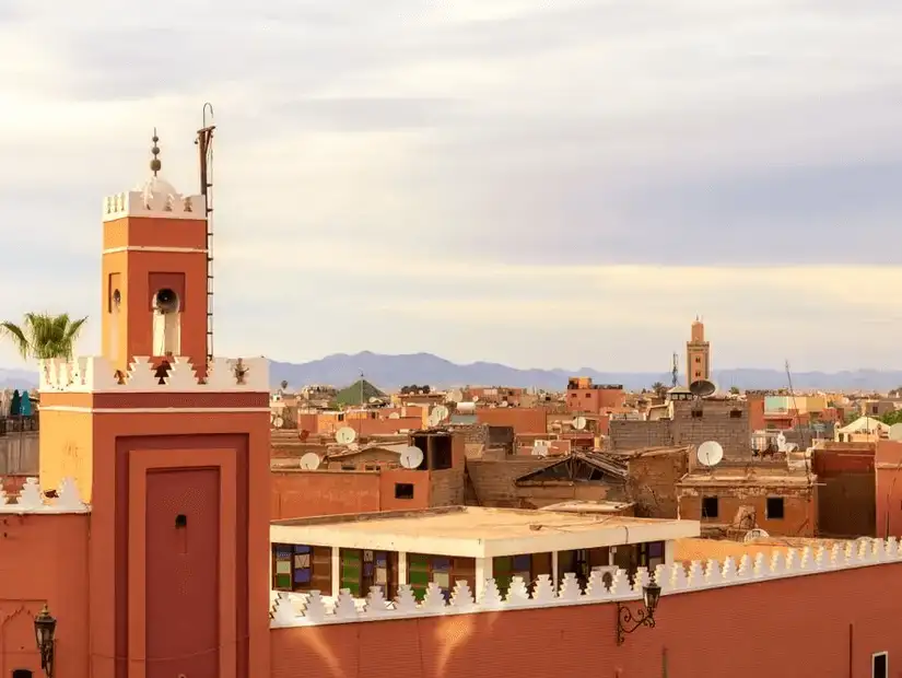 Overlooking the terracotta rooftops of Marrakesh with mountains in the distance.