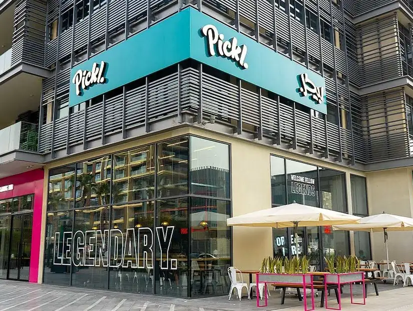 A modern, vibrant restaurant with bold signage and an inviting outdoor seating area.