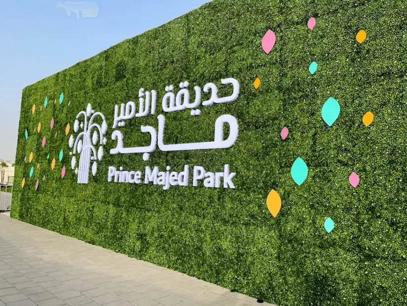 Lush green foliage wall with colorful accents welcoming visitors to Prince Majid Park.