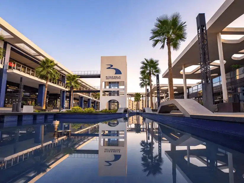 A reflection of Riverwalk Dining & Shopping Center on the water, highlighting the symmetry and design of the complex.