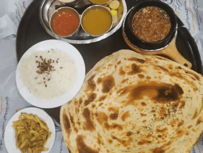 Traditional Yemeni meal with rice, flatbread, and a selection of savory stews.