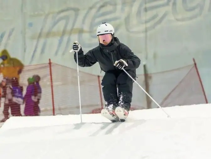 Skier on indoor snowy slope.