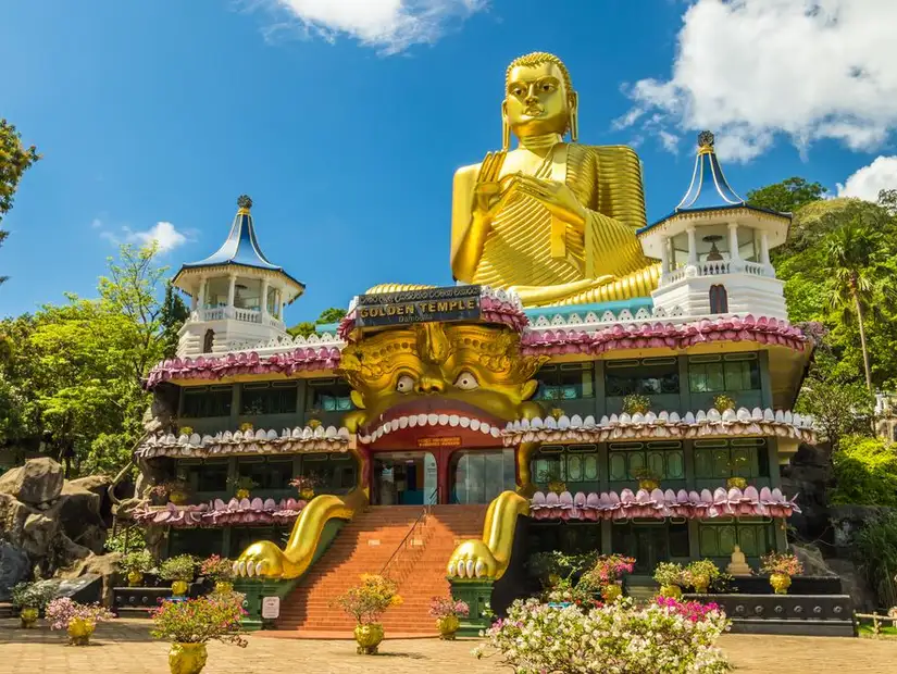 The colorful front of the Golden Temple of Dambulla with a giant Buddha statue