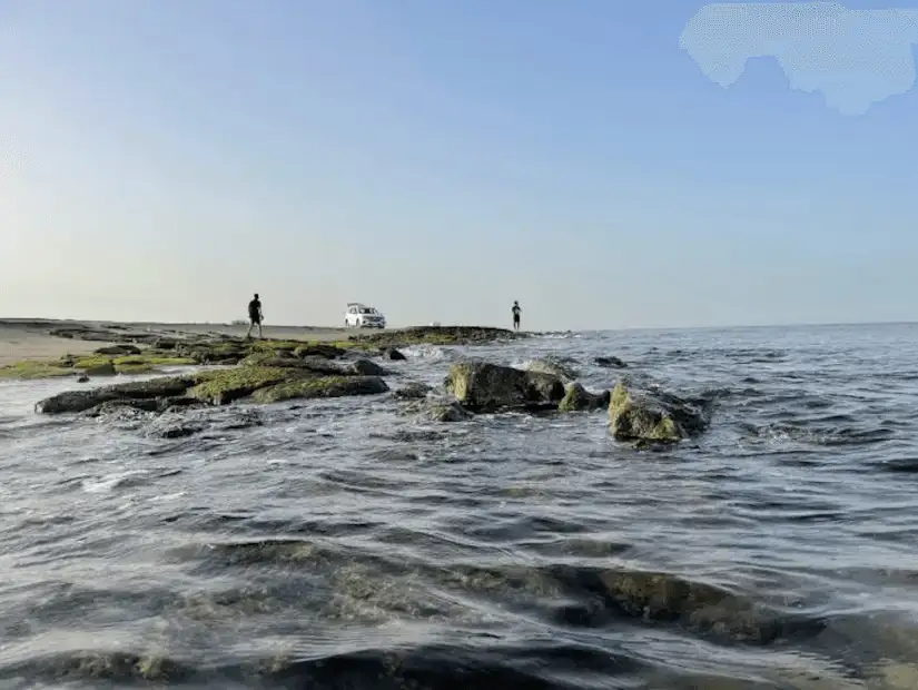 Rocky seaside landscape with figures in the distance, highlighting the rugged beauty of a natural shoreline.