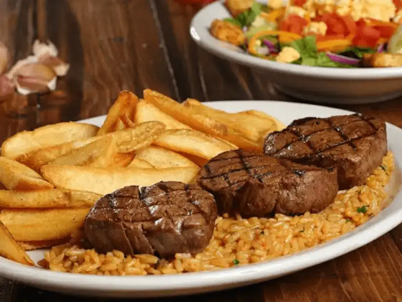 Grilled steak medallions served with seasoned fries and tomato rice pilaf.