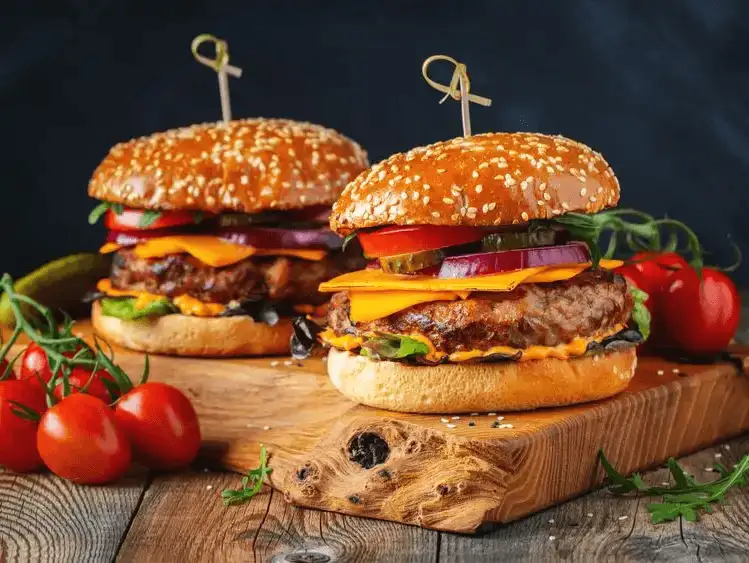 Gourmet burgers with all the trimmings, presented on a rustic wooden board.