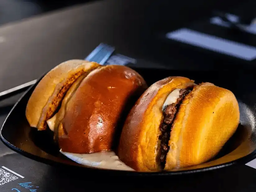 A close-up of two deliciously prepared sandwiches with golden buns, served on a sleek black plate.