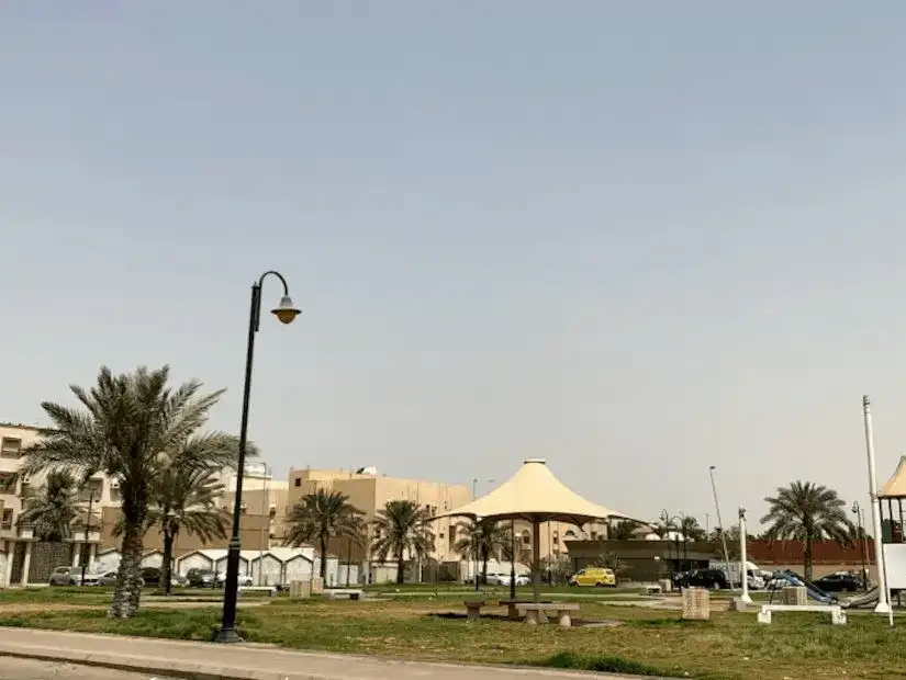 Park benches and shaded areas amidst residential buildings in Tihama Park.