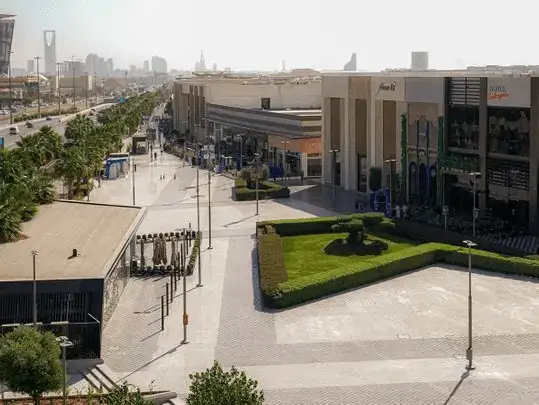 An aerial view of a modern outdoor shopping center with neatly arranged greenery and a spacious walkway.