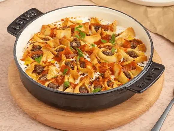 Baked pasta with sausage and cheese in a cast iron pan.