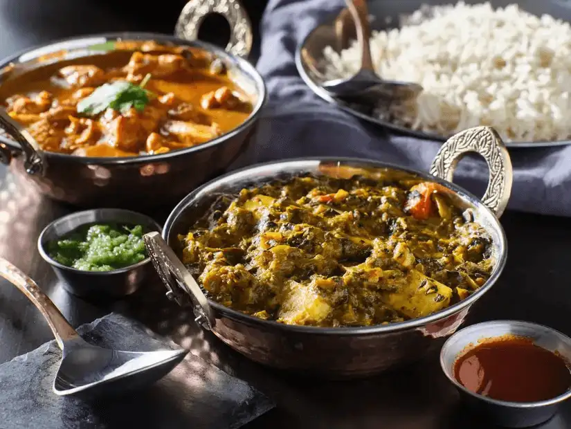 Assorted Indian dishes including chicken curry and paneer in a rich sauce.