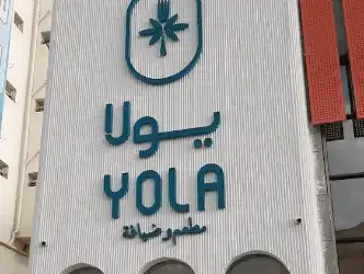 Exterior signage of 'YOLA' with a stylized logo on a modern building facade.