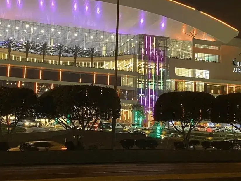 Modern shopping mall illuminated with vibrant lights at night.