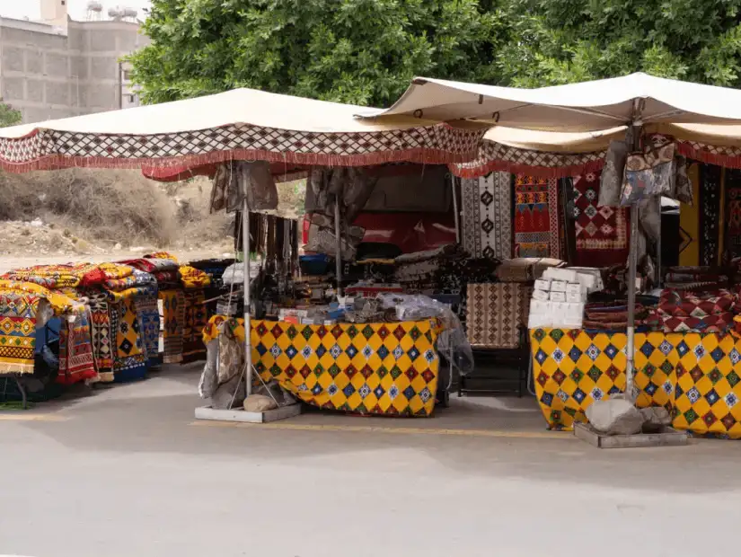 Colorful outdoor market stalls selling traditional textiles and crafts.