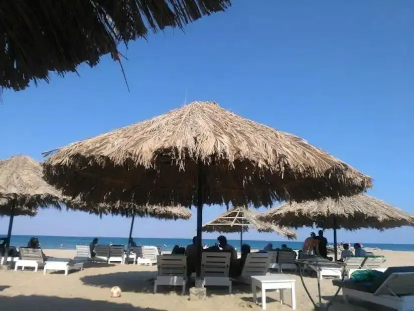 A calm beach with sun umbrellas and chairs, offering a peaceful getaway by the sea.