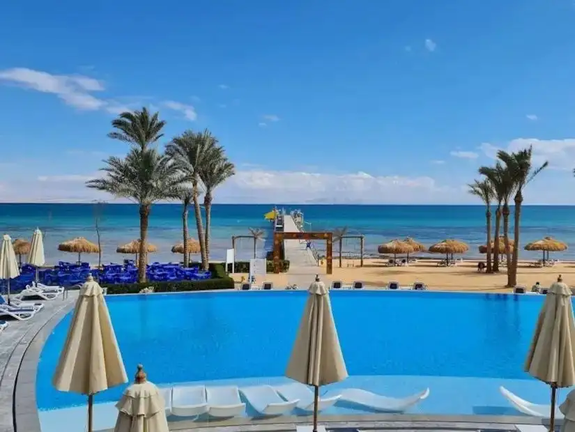 A tranquil beach scene in Ain Sokhna, with clear water and palm trees lining the coast.