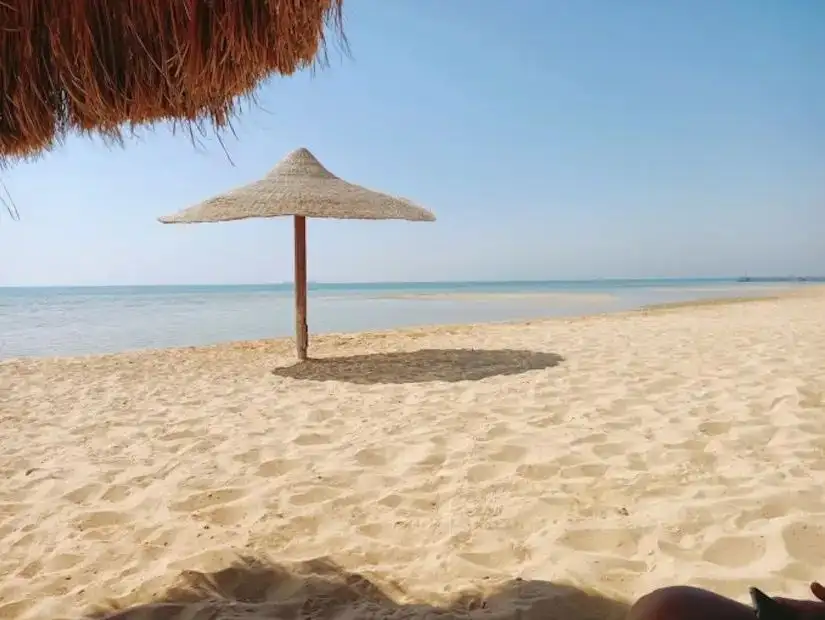 The tranquil beach of Ain Sokhna with a view of the sea, where a few people are enjoying the water.