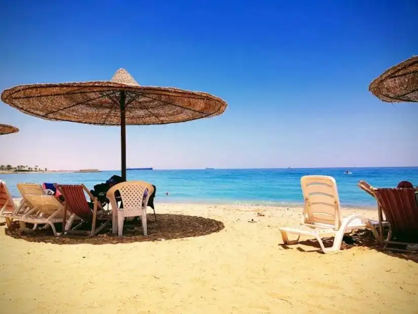 A beachside view in Ain Sokhna with beach umbrellas and a tranquil, clear sea stretching into the horizon.
