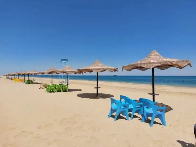 A peaceful beach scene in Ain Sokhna with umbrellas and lounge chairs by the clear blue water.